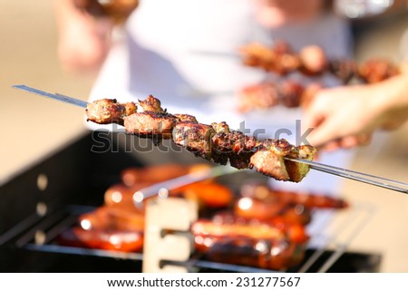 Young friends having barbecue party. Hands with skewers, close-up