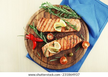 Grilled salmon with spices on cutting board on wooden background
