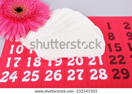 Sanitary pads, calendar, towel and pink Gerber on light background