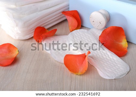 Sanitary pads in box and rose petals on light grey background