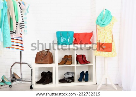Different clothes on hangers, shoes on shelves in shop