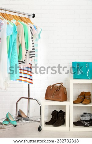 Different clothes on hangers, shoes on shelves in shop
