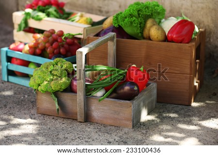Fresh organic fruits and vegetables in wooden boxes outdoors