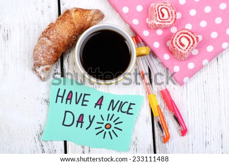 Composition of coffee, fresh croissant and paper card on napkin, on wooden background