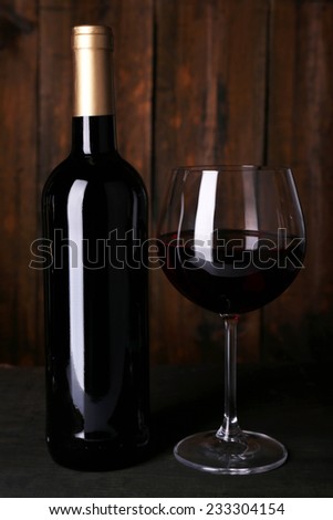 Red wine glass and bottle of wine on wooden background