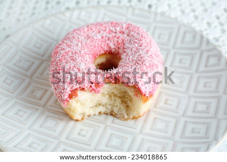 Bitten delicious donut on plate close-up