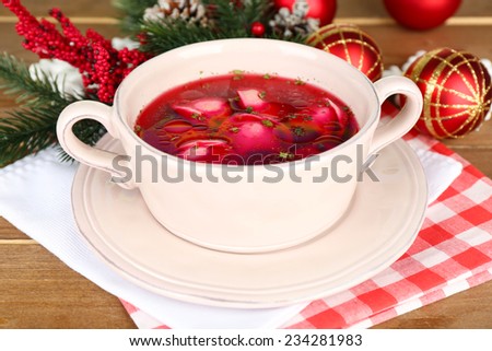 Traditional polish clear red borscht with dumplings and Christmas decorations on wooden table background