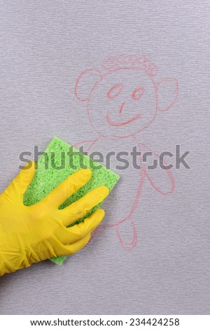 Hand in glove wiping children drawing on wallpaper