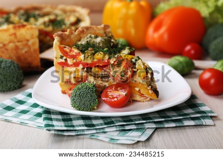 Piece of Vegetable pie with broccoli, peas, tomatoes and cheese on plate, on wooden background