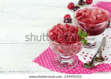 Closeup of cherry granita in glass bowl, on color wooden background
