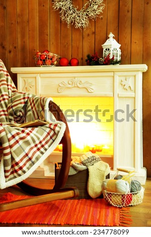 Rocking chair with plaid near fireplace