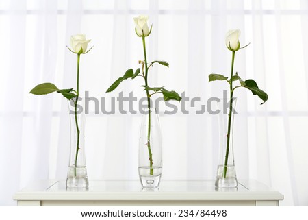 Beautiful bouquet of flowers in vases on window background