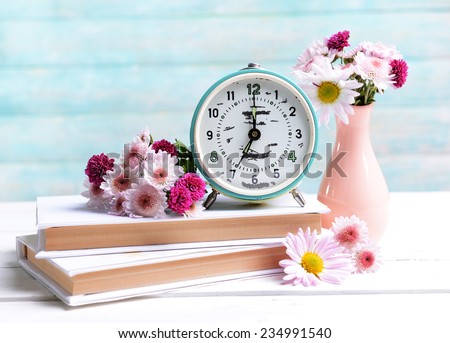 Beautiful flowers in vase on table on light blue background