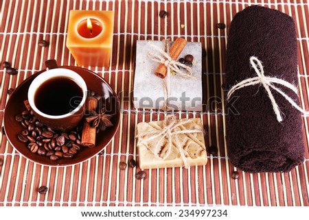 Organic soap with coffee beans,   cup with coffee, candle, towel  on bamboo mat background, Coffee spa concept