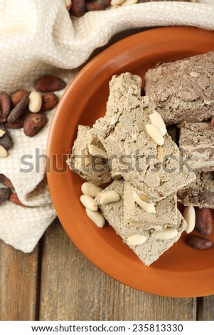Two kinds of sunflower halva- with cocoa and peanuts on plate, on wooden background
