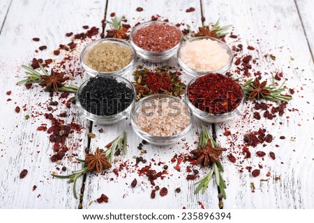 Spices in glass round bowls with herbs on wooden background