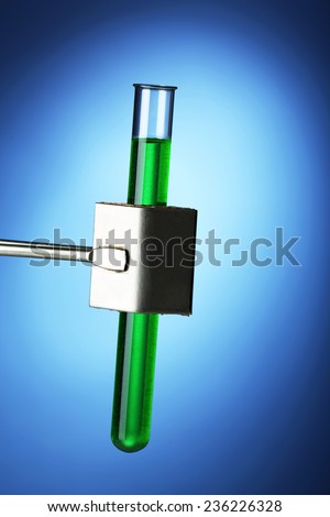Laboratory glass test tube filled  color liquid held in specialized  clamp during  scientific experiment
