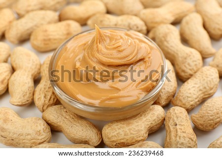Creamy peanut butter in bowl on peanut background, close-up