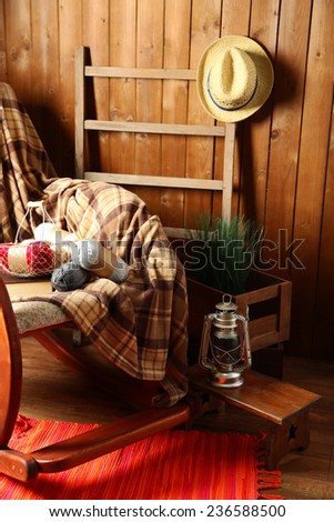Rocking chair with plaid and yarn for knitting near wooden wall