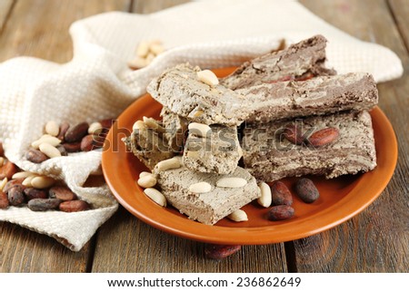Two kinds of sunflower halva- with cocoa and peanuts on plate, on wooden background