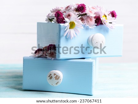 Beautiful flowers in boxes on table on light background