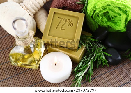 Handmade soap with the branches of rosemary, bottle with rosemary oil and towels, close-up. Rosemary spa concept