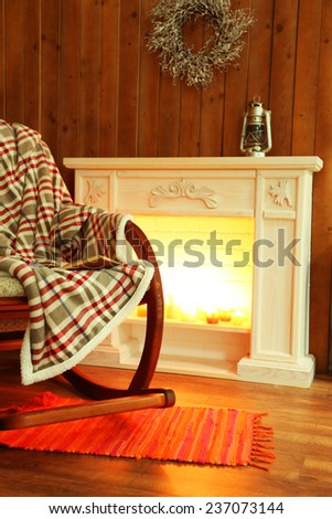 Rocking chair with plaid near fireplace