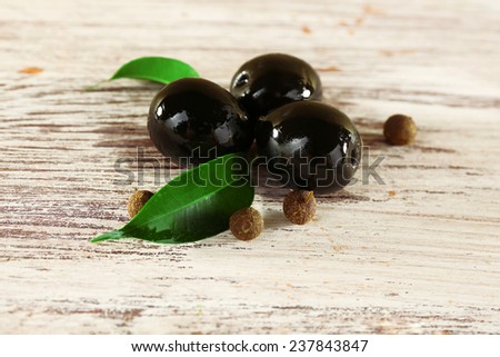 Tree black olives with leaf and peas on painted wooden background
