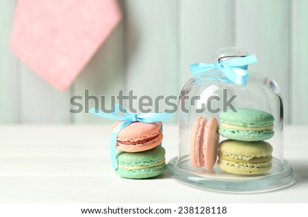 Gentle colorful macaroons in glass bell jar on color wooden table background