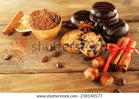 Chocolate cookies with bowl of cocoa, nuts, coffee beans, slice of lemon and cinnamon on rustic background