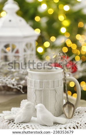 Mug with hot drink and Christmas decorations on fir tree background