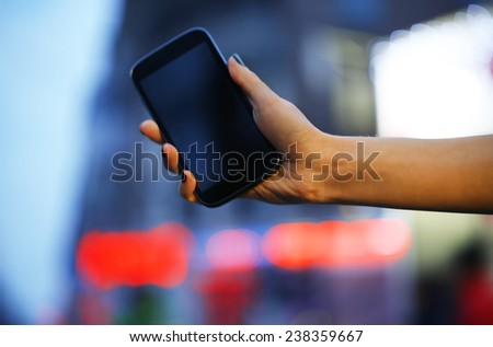 Mobile phone in woman hand on night city light background