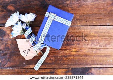 Happy Father\'s Day with gift box, ribbon, bouquet of flowers and piece of paper on wooden background