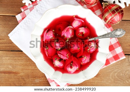 Traditional polish clear red borscht with dumplings and Christmas decorations on wooden table background