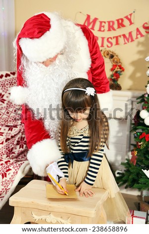 Little cute girl writing letter to Santa Claus near Christmas tree at home
