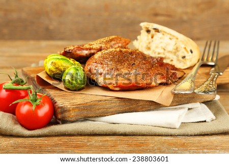 Roasted meat and vegetables on cutting board, on wooden table background