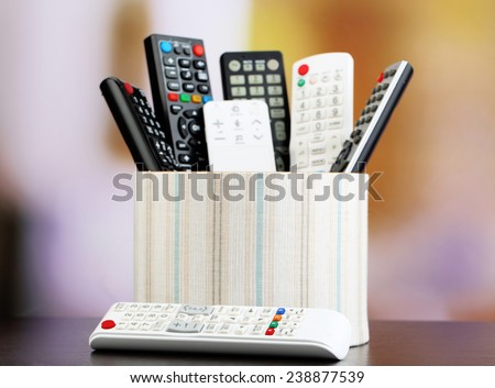 Many remote control devices in basket on bright background