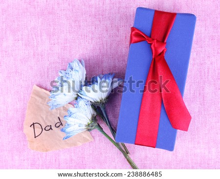 Happy Father\'s Day with gift box, flowers and piece of paper on texture background