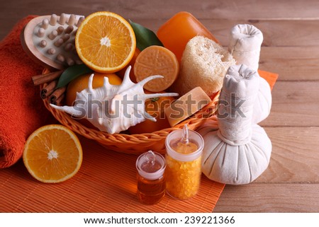 Spa accessories in wicker basket with rolled towel and compress balls on color bamboo mat on wooden background