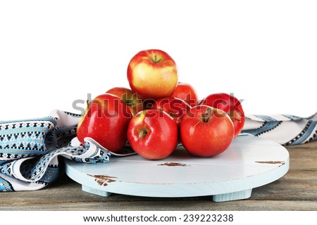 Heap of apples on board with dish cloth on wooden table isolated on white background