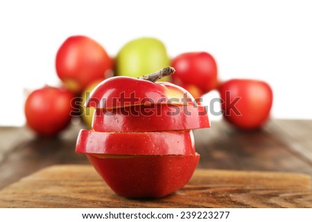 Cut apple on wooden table with other apples isolated on white background