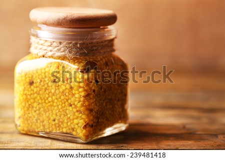 Dijon Mustard in glass jar on wooden background