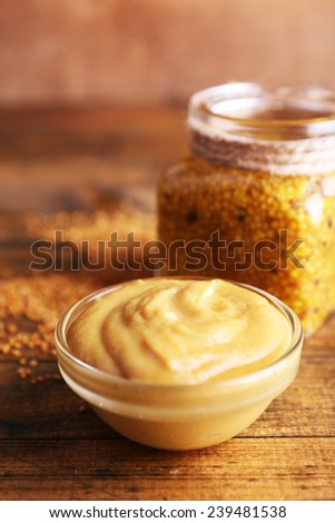 Dijon Mustard in glass jar and mustard sauce in glass bowl on wooden background