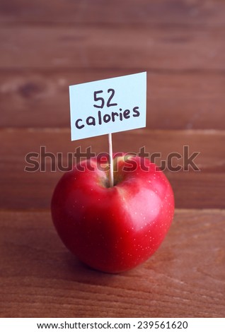 Red apple with calories count label on wooden table background