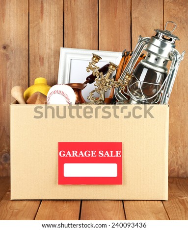 Box of unwanted stuff ready for a garage sale on wooden background
