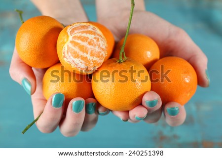Hands holding ripe tangerines, close up