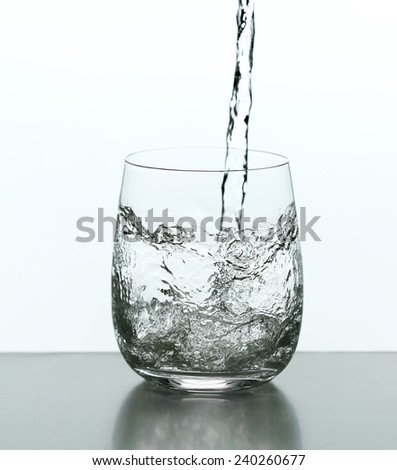 Pouring water from bottle on  glass isolated on white