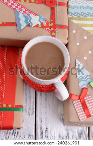 Hand-made Christmas gifts with cup of coffee on wooden background
