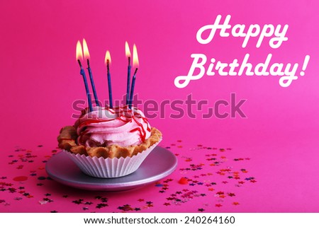 Birthday cup cake with candles and colorful stars on pink background