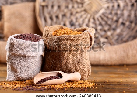 Mustard seeds in bags on  wooden background